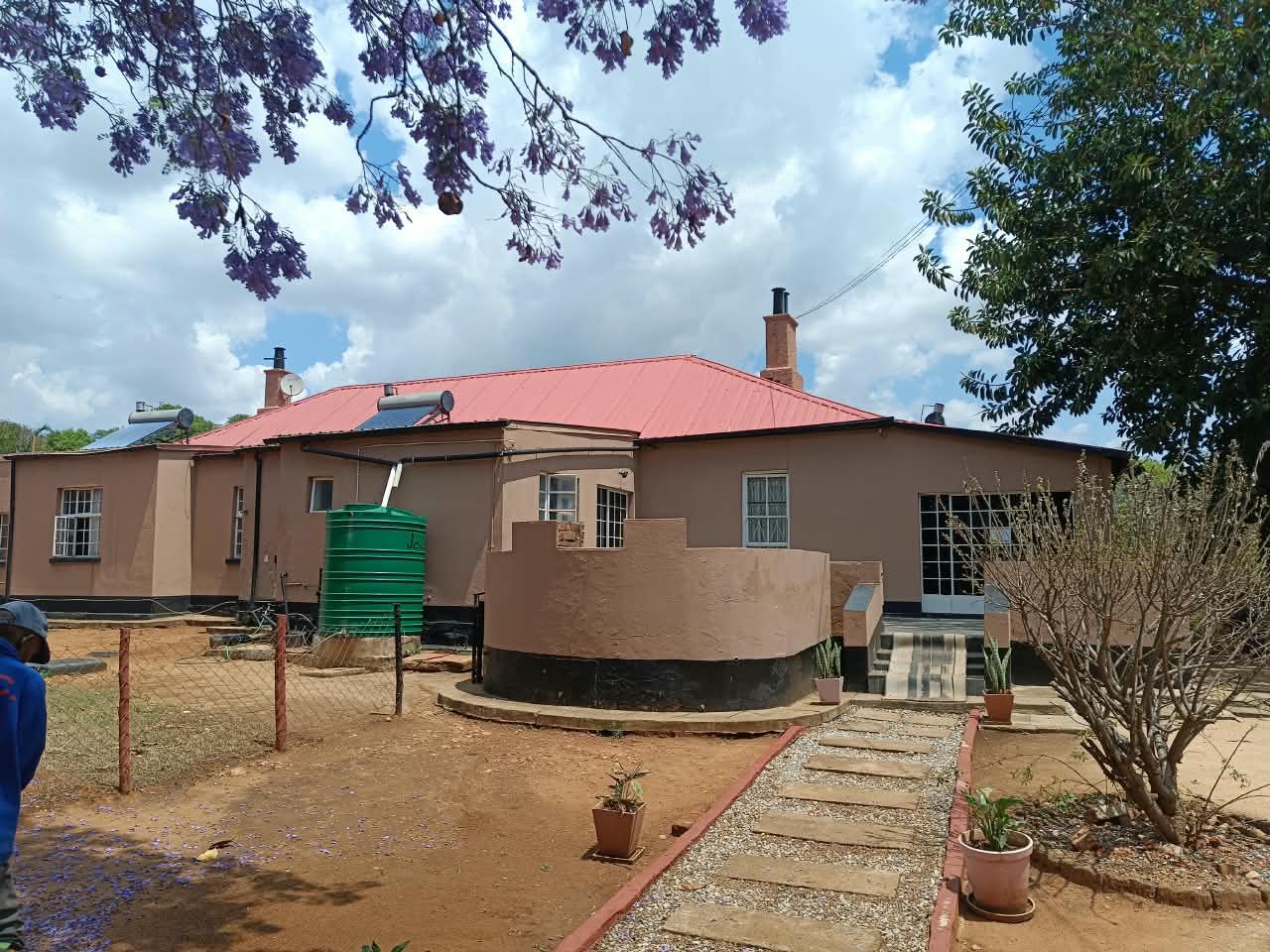 The school building with its newly painted red roof under a jacaranda tree