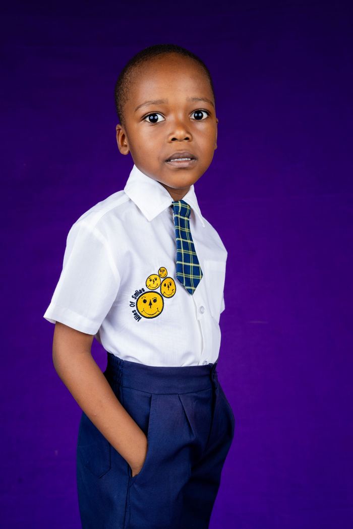 A Miles of Smiles learner in a white shirt with the smiley-face crest and plaid tie